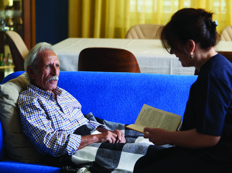 volunteer reading to senior man